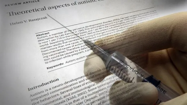 Syringe poised over a medical article discussing the theoretical aspects of autism and vaccination