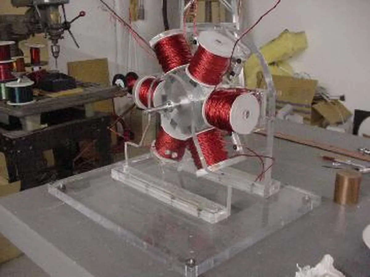 A clear acrylic Tesla coil model with red wire coils and a circular base, demonstrating electrical engineering principles